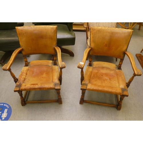 190 - A pair of 1930w oak framed chairs with brown hide upholstered backs and seats, raised on block legs