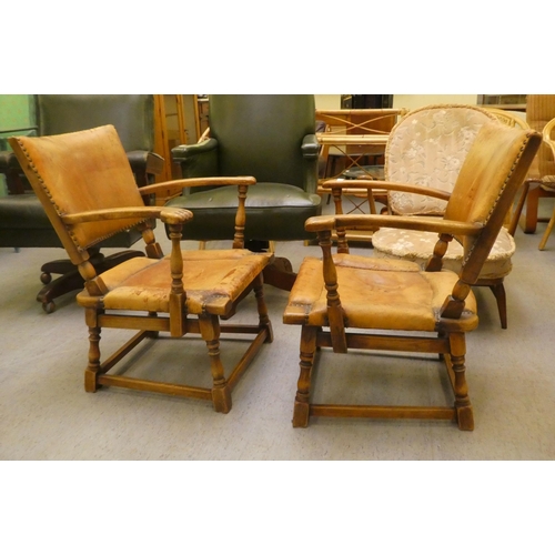 190 - A pair of 1930w oak framed chairs with brown hide upholstered backs and seats, raised on block legs