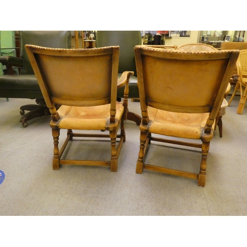 190 - A pair of 1930w oak framed chairs with brown hide upholstered backs and seats, raised on block legs