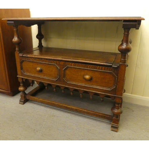 192 - A 1930s oak monks bench with a carved lift and slide back, over a hinged seat, raised on splayed fee... 