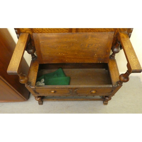 192 - A 1930s oak monks bench with a carved lift and slide back, over a hinged seat, raised on splayed fee... 