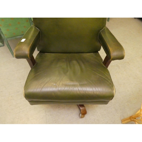 206 - A mid 20thC faux green hide upholstered swivel office chair, raised on a splayed pedestal base