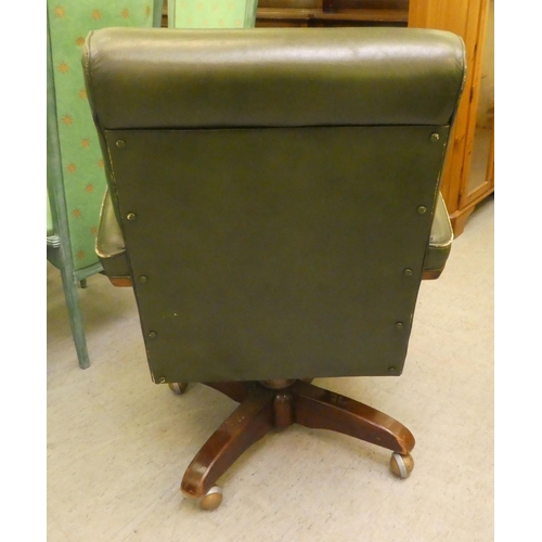 206 - A mid 20thC faux green hide upholstered swivel office chair, raised on a splayed pedestal base