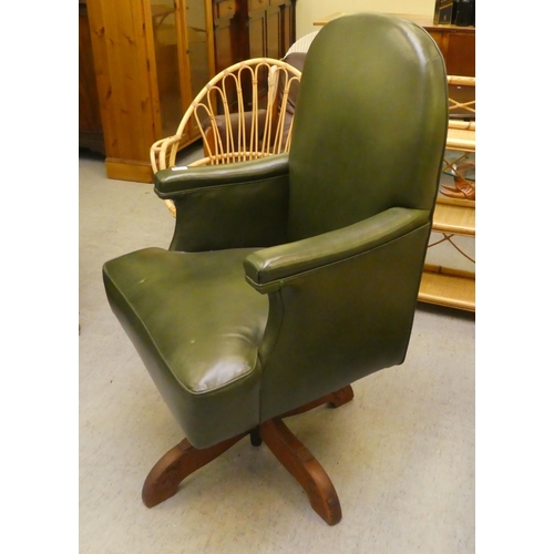 211 - A mid 20thC faux green hide upholstered swivel office chair, raised on a splayed pedestal base