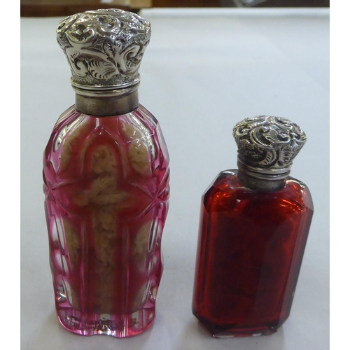 222 - Two late Victorian Cranberry glass scent bottles, each with a hinged silver lid&nbsp; indistinct mar... 