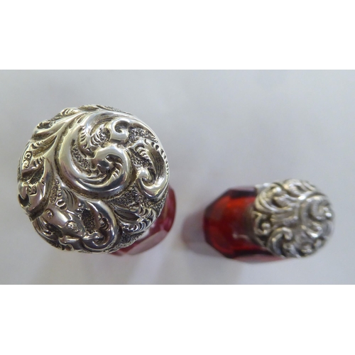 222 - Two late Victorian Cranberry glass scent bottles, each with a hinged silver lid&nbsp; indistinct mar... 