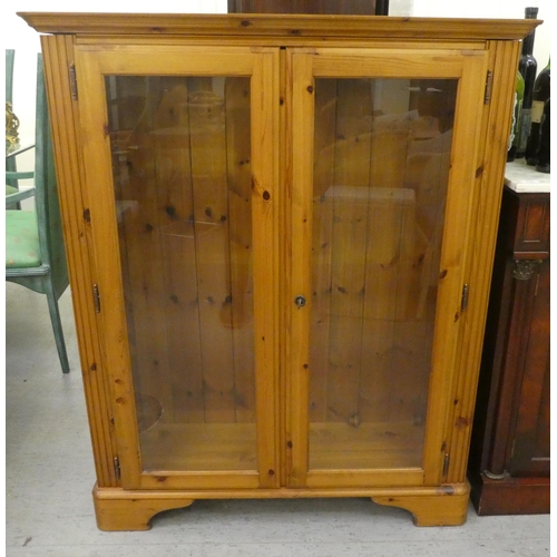 262 - A modern stained pine bookcase with two glazed doors, on a bracket plinth  48