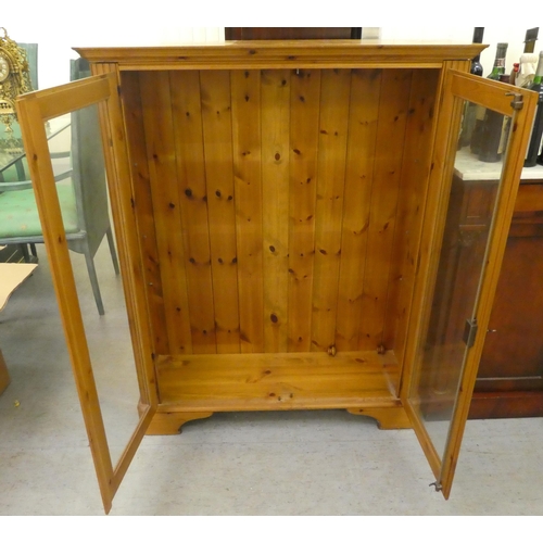 262 - A modern stained pine bookcase with two glazed doors, on a bracket plinth  48