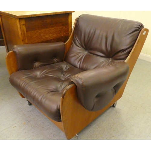 268 - A 1960/70s G-Plan teak framed easy chair with a faux brown hide upholstered back and seat