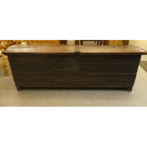 270 - A mid 18thC boarded oak chest with a hinged lid, raised on planked feet  17