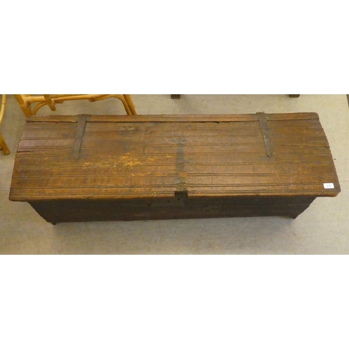 270 - A mid 18thC boarded oak chest with a hinged lid, raised on planked feet  17