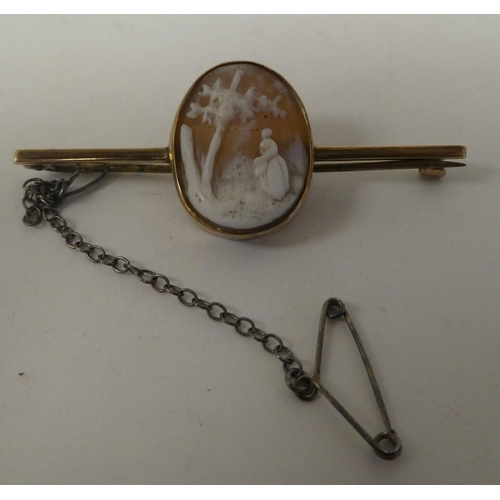 76 - A yellow metal bar brooch, set with an oval cameo, a study of a woman in a woodland