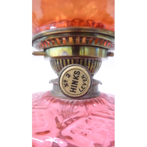 107 - A reproduction of a Victorian style brass oil lamp with a cranberry coloured glass reservoir and an ... 