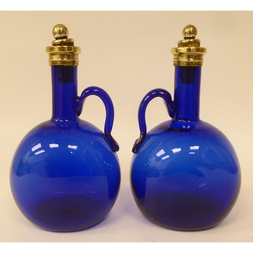 12 - A pair of antique Bristol blue glass decanters of  bulbous form with narrow necks, strap handles, br... 