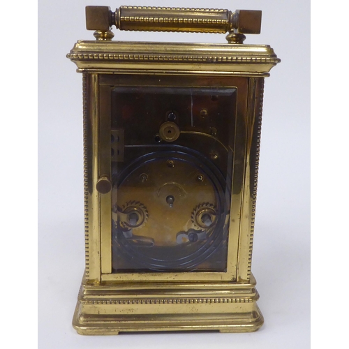 13 - A mid 20thC lacquered brass cased carriage clock with bead bordered ornament, bevelled glass panels ... 