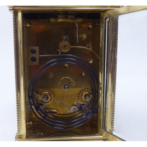 13 - A mid 20thC lacquered brass cased carriage clock with bead bordered ornament, bevelled glass panels ... 