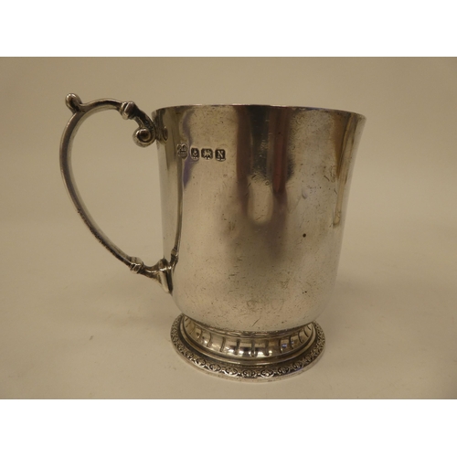 28 - A silver Christening tankard with a flared rim and applied C-scrolled loop handle, on a decoratively... 