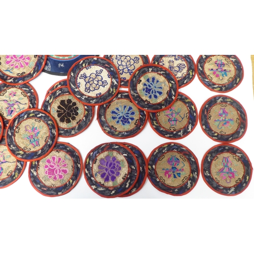 36 - Approx. thirty 20thC Chinese fabric roundel table mats, embroidered in coloured silk and yellow meta... 