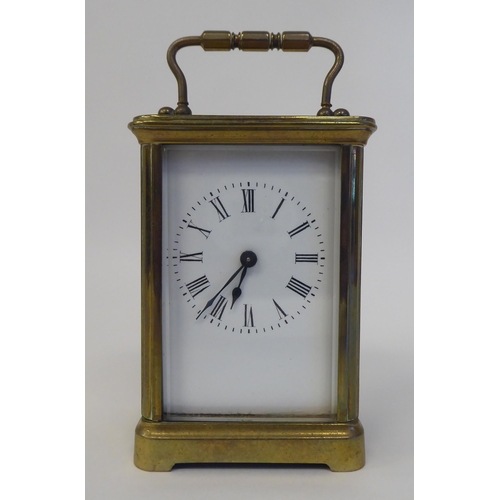 37 - A mid 20thC lacquered brass cased carriage timepiece with bevelled glass panels, a folding top handl... 