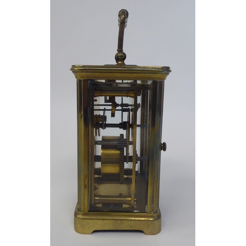 37 - A mid 20thC lacquered brass cased carriage timepiece with bevelled glass panels, a folding top handl... 