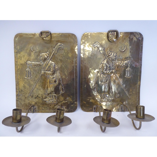 61 - A pair of late 19th/early 20thC brass girandoles, the rectangular backplates embossed with an elderl... 