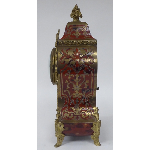 81 - A 19thC French red boulle cased mantel clock of waisted form with gilt metal mounts; the bell strike... 