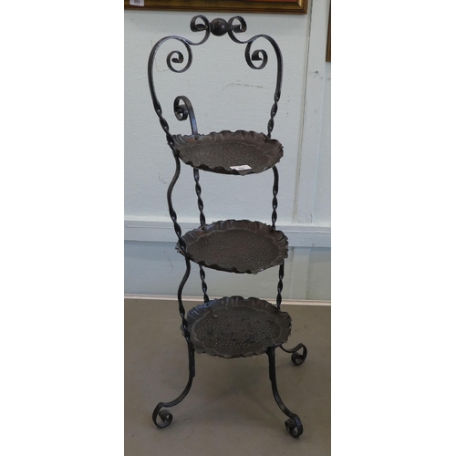 84 - An Art Nouveau inspired wrought iron framed and spot-hammered three tier brass tray cakestand  ... 