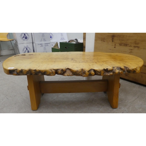 85 - A modern worked burr elm naturalistic coffee table, raised on light oak planked legs, united by a st... 