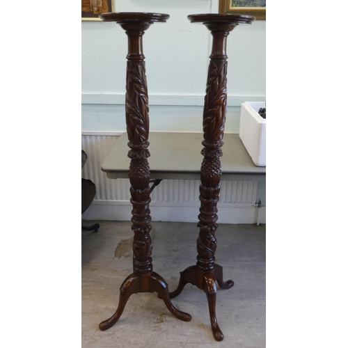 88 - A pair of modern carved mahogany torcheres, raised on tripod bases  57