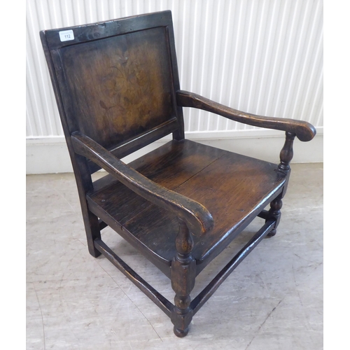 112 - An antique finished, dark stained oak floral marquetry, panelled back, low, open arm chair with a so... 