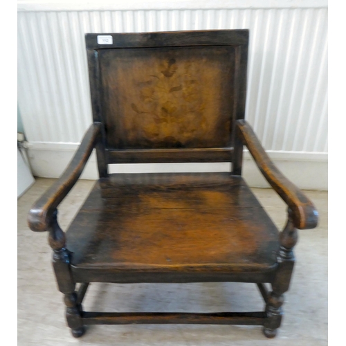 112 - An antique finished, dark stained oak floral marquetry, panelled back, low, open arm chair with a so... 