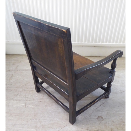 112 - An antique finished, dark stained oak floral marquetry, panelled back, low, open arm chair with a so... 