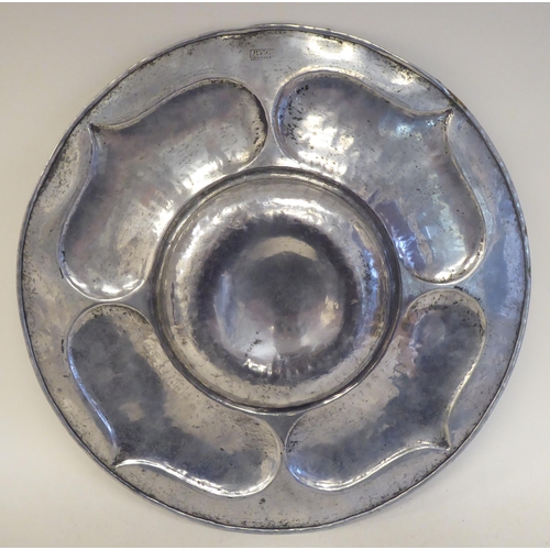 116 - A Pewtal dish with a depressed centre, the wide rim ornamented in Art Nouveau inspired designs ... 