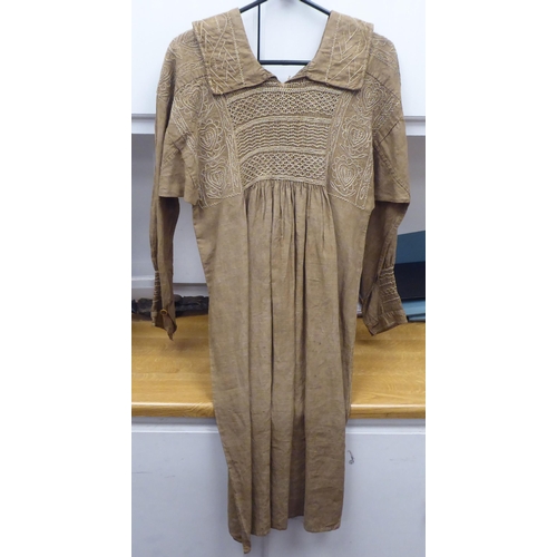 122 - A Continental artisan's brown calico pleated dress with decorative, stone coloured embroidery and sm... 