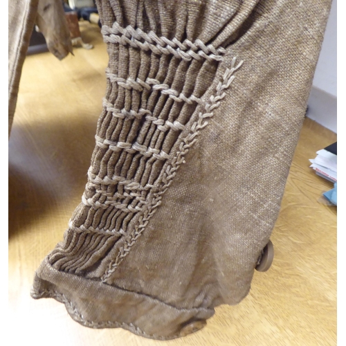 122 - A Continental artisan's brown calico pleated dress with decorative, stone coloured embroidery and sm... 