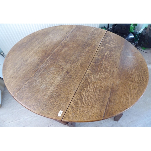 123 - An 18th/19thC style rustic oak drop-leaf dining table with an end drawer, the oval top raised on tur... 