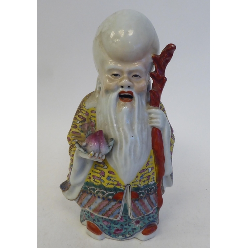 128 - An early 20thC Chinese porcelain figure, a robed, standing scholar, decorated in famille rose and hi... 