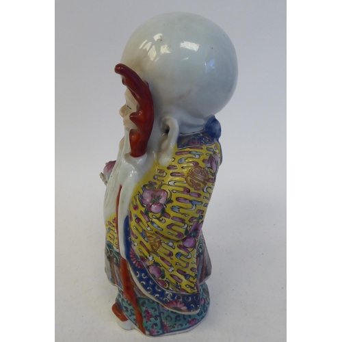 128 - An early 20thC Chinese porcelain figure, a robed, standing scholar, decorated in famille rose and hi... 