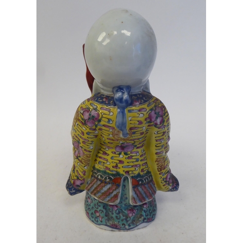 128 - An early 20thC Chinese porcelain figure, a robed, standing scholar, decorated in famille rose and hi... 