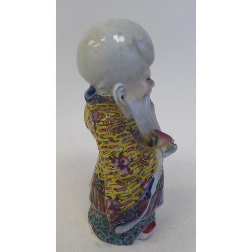 128 - An early 20thC Chinese porcelain figure, a robed, standing scholar, decorated in famille rose and hi... 