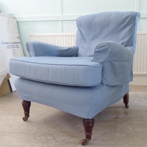 130 - A late Victorian library chair with a level back and enclosed arms, re-upholstered in patterned blue... 