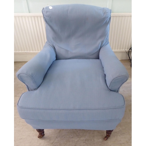 130 - A late Victorian library chair with a level back and enclosed arms, re-upholstered in patterned blue... 