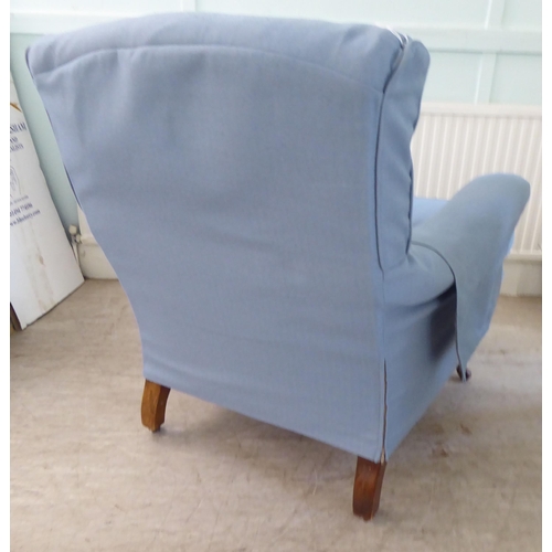 130 - A late Victorian library chair with a level back and enclosed arms, re-upholstered in patterned blue... 