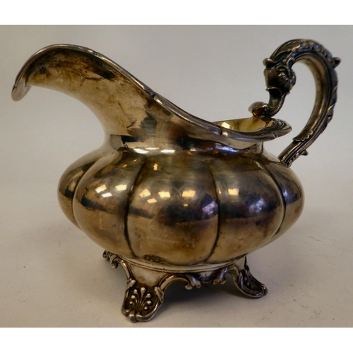 131 - A George IV silver melon shape cream jug with a flared rim on S-scrolled handle, on a shell cast foo... 