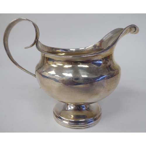 132 - A silver pedestal cream jug of squat, bulbous form with an applied wire rim and C-scrolled handles&n... 