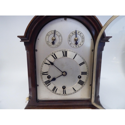 137 - A late 19th/early 20thC mahogany round arched cased mantel clock with a full-height window, on a pli... 