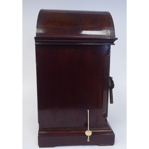 137 - A late 19th/early 20thC mahogany round arched cased mantel clock with a full-height window, on a pli... 