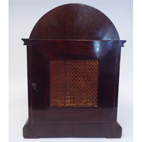 137 - A late 19th/early 20thC mahogany round arched cased mantel clock with a full-height window, on a pli... 