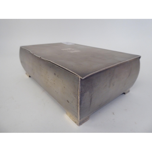 143 - A silver cigarette box with allover engine turned decoration, the hinged lid enclosing a maple lined... 