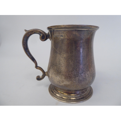 144 - An Edwardian silver Christening mug of baluster form with a hollow, double C-scrolled handle, on a s... 